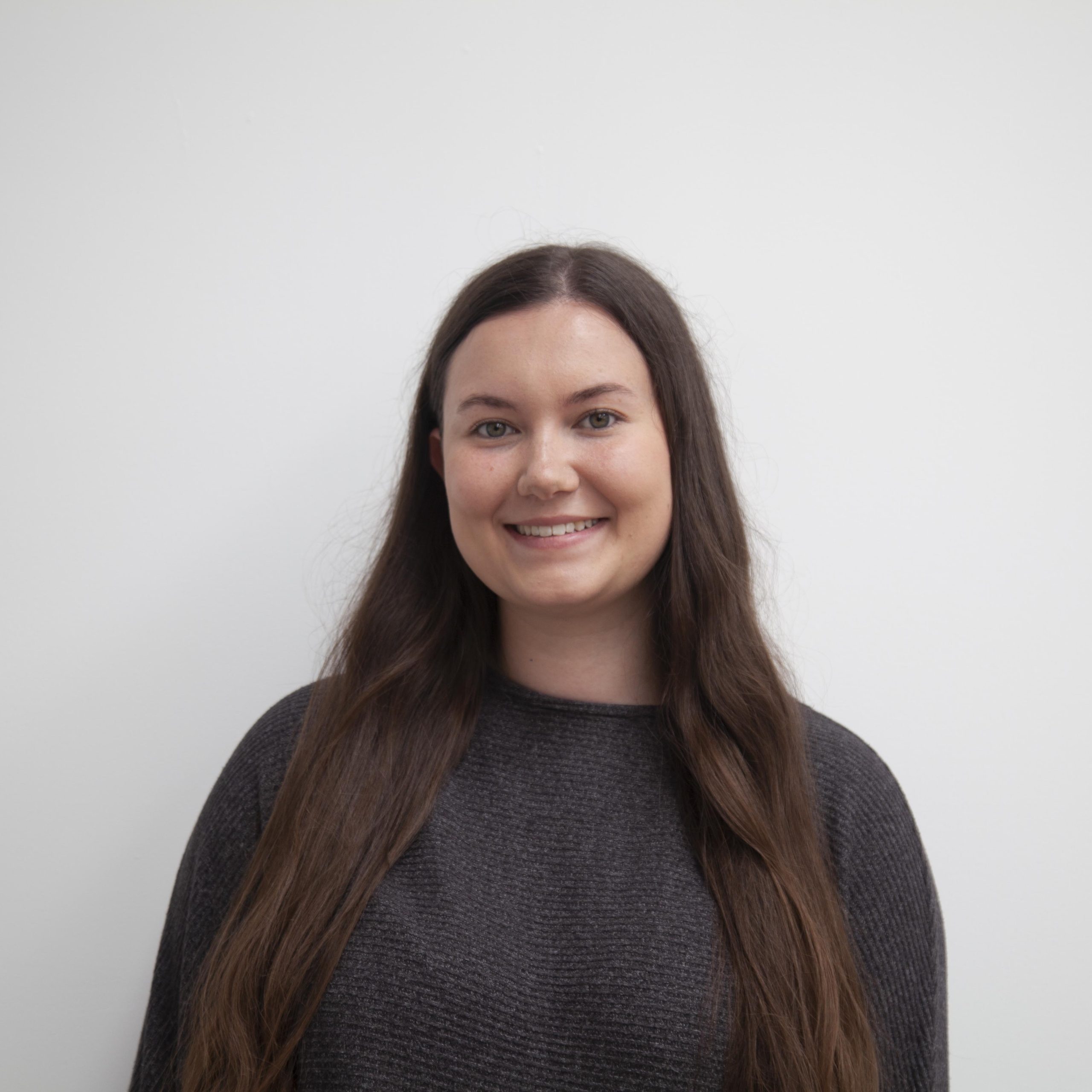 USB2U new staff member Calypso Eales poses for a photo on a white background, wearing a dark jumper