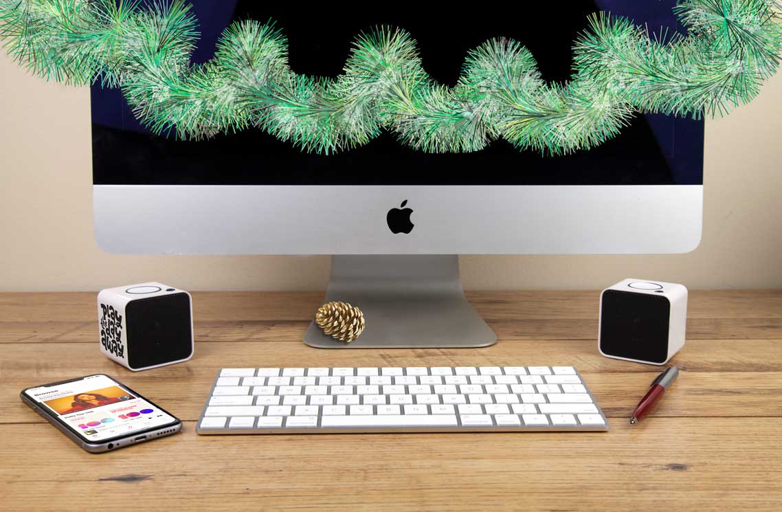 branded bluetooth speakers on a desk with a mac and keyboard with festive decorations