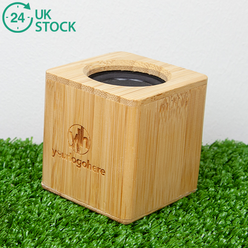 Bamboo engraved speaker with 'your logo here' branded on. Sitting on a grass background with an icon that says 24 hours UK stock.
