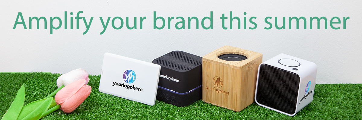 Bluetooth speakers branded with 'your logo here' on a grass background with the text "Amplify your brand this summer"